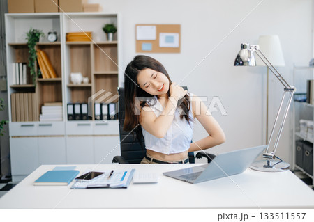 Overworked young Asian businesswoman office worker suffering from neck pain after had a long day at her office desk. 133511557