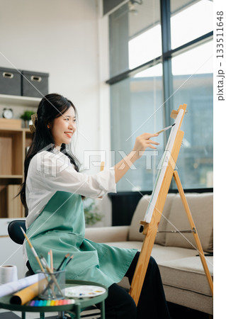 Asian Female painter do artwork in art workshop, painting supplies, oil pastels, two canvas easel, creative space Asian Female painter do artwork in art workshop, painting supplies, oil pastels, two canvas easel, creative space 133511648