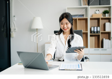 businesswoman working at office with laptop, tablet and taking notes on the paper. 133511659