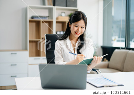 businesswoman working at office with laptop, tablet and taking notes on the paper. businesswoman working at office with laptop, tablet and taking notes on the paper. 133511661