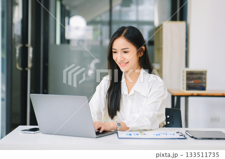 Young Asian businesswoman working with working notepad, tablet and laptop documents talking on the smartphone, tablet and laptop video call Young Asian businesswoman working with working notepad, tablet and laptop documents talking on the smartphone, tablet and laptop video call 133511735