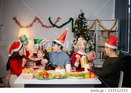 Joyful Asian family gathered for a Christmas feast, exchanging gifts, and celebrating the holiday season with love Joyful Asian family gathered for a Christmas feast, exchanging gifts, and celebrating the holiday season with love 133512333