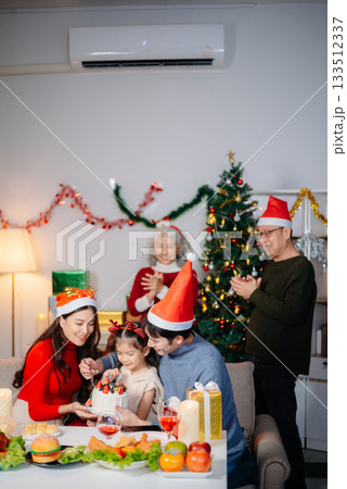 Joyful Asian family gathered for a Christmas feast, exchanging gifts, and celebrating the holiday season with love Joyful Asian family gathered for a Christmas feast, exchanging gifts, and celebrating the holiday season with love 133512337