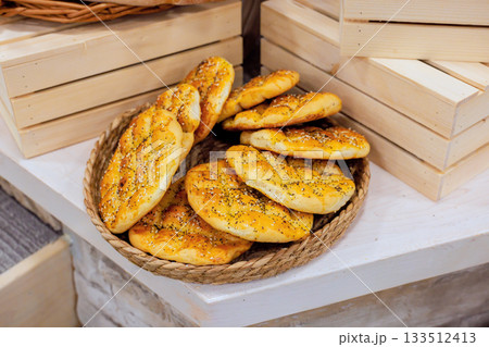 Warm bread rolls displayed on rustic basket, tempting customers at local bakery Warm bread rolls displayed on rustic basket, tempting customers at local bakery 133512413