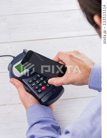 Man holding credit card reader and mobile phone Man holding credit card reader and mobile phone 133513114