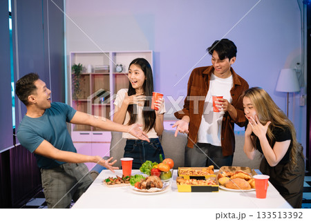 Young Asian Friends Celebrating with Laughter and Food at a Modern Evening Party 133513392