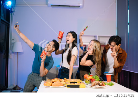 Young Asian Friends Celebrating with Laughter and Food at a Modern Evening Party Young Asian Friends Celebrating with Laughter and Food at a Modern Evening Party 133513419