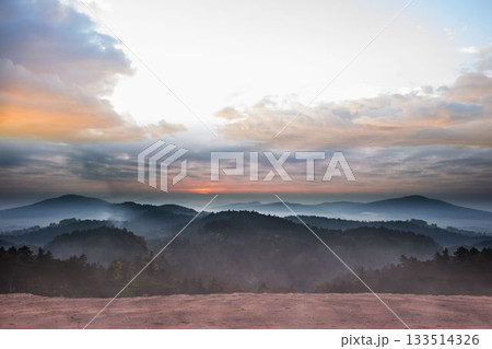 Misty hills and rocky plateau edge are featuring flat design with sun rays and mist layers 133514326