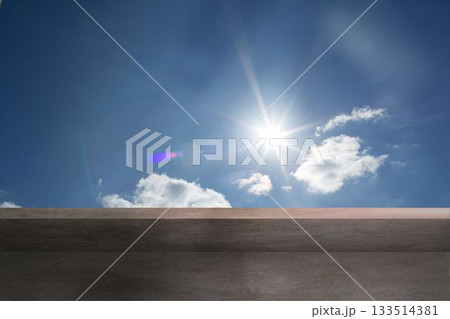 Flat design showing concrete terrace ledge framing bright sun with lens flare drifting clouds 133514381