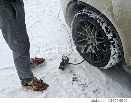 Pumping Car Tire in Snowy Winter Conditions 133514991