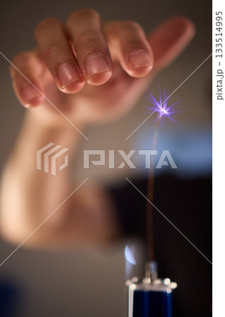 Hands manipulating metal spheres generate vibrant electrical plasma display, Laboratory scene showcasing coil discharging luminous sparks with scientific precision 133514995