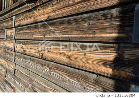 経年変化した古い横張りの板壁とさびた金属バンドのテクスチャー 133516804