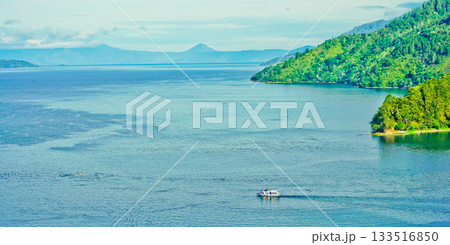 Beautiful view of the lake with a backdrop of green hills and clear skies Beautiful view of the lake with a backdrop of green hills and clear skies 133516850