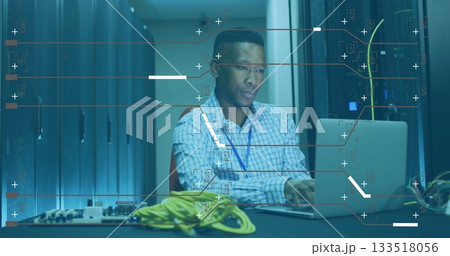 Tech in shirt monitoring servers using laptop in data center, with yellow, green ethernet cables Tech in shirt monitoring servers using laptop in data center, with yellow, green ethernet cables 133518056