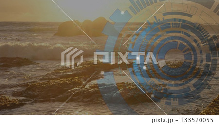 Crashing sunlit ocean waves hitting jagged rocky shoreline at sunset, with digital HUD graphic 133520055