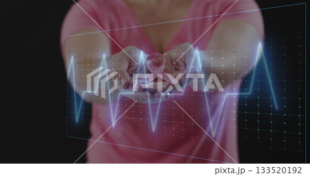 Holding mid adult woman extending hands forward displaying pink ribbon with ECG overlay in studio Holding mid adult woman extending hands forward displaying pink ribbon with ECG overlay in studio 133520192