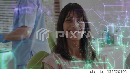 Smiling patient sitting in dental chair at dental clinic, with digital overlay, instrument tray 133520193