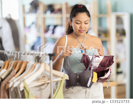 Attentive young girl choosing bra in clothing store Attentive young girl choosing bra in clothing store 133523735