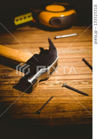 Claw hammer is resting on wooden workbench, flat design showing scattered nails and tape measure Claw hammer is resting on wooden workbench, flat design showing scattered nails and tape measure 133525318
