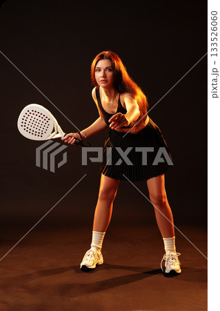 Young woman preparing to hit a ball in sport with bright lighting and dark background Young woman preparing to hit a ball in sport with bright lighting and dark background 133526060
