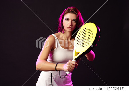Woman practicing her tennis skills in a studio with dramatic lighting effects 133526174