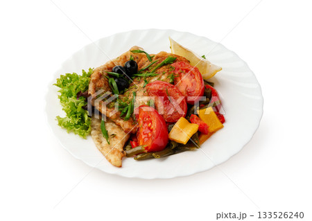 Delicious fried fish with fresh vegetables and herbs served on a white plate 133526240