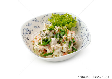 Fresh salad with vegetables and herbs served in a decorative bowl at a dining table 133526283