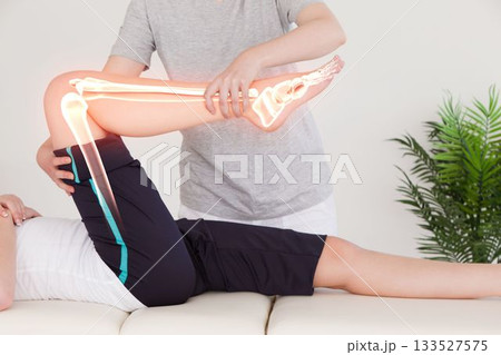 Physiotherapist holding injured woman leg Physiotherapist holding injured woman leg 133527575
