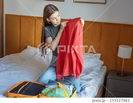 Woman packing clothes for travel trip preparing suitcase 133527983