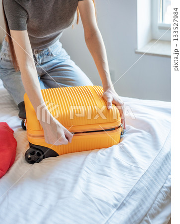 Woman packing suitcase on bed preparing for travel 133527984