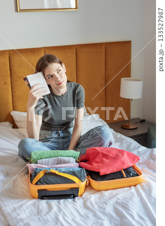 Woman dreaming of travel while packing suitcase for vacation 133527987