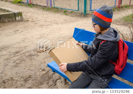 teenager in profile sits on a bench with a small box teenager in profile sits on a bench with a small box 133529296