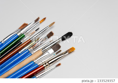 collection of art brushes of different sizes displayed on a white table. Overhead horizontal photo. Craft hobby background. Recomforting, destressing hobby, art therapy 133529357