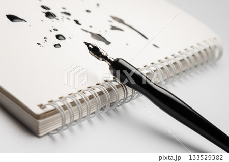 fountain pen rests on a blank notebook on a white, smooth table, close-up. The blots symbolize an idea or inspiration. Creative concept fountain pen rests on a blank notebook on a white, smooth table, close-up. The blots symbolize an idea or inspiration. Creative concept 133529382