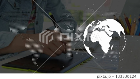 Holding stylus, artist drawing on tablet at desk, showing colored pencils and world map overlay Holding stylus, artist drawing on tablet at desk, showing colored pencils and world map overlay 133530124