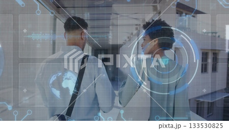 Walking colleagues carrying bag and exploring glass windowed corridor, with holographic interface 133530825