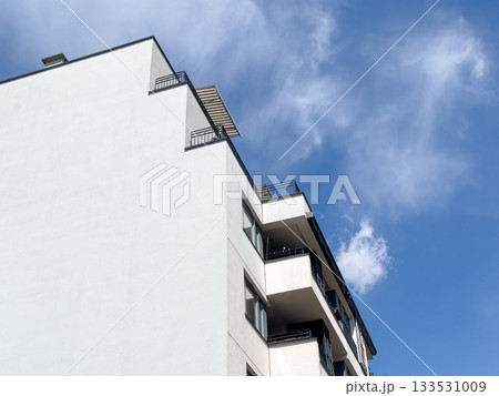 Building rises against cloudy city sky. Tall modern skyscraper architecture shows windowed highrise 133531009