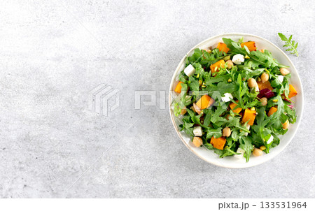 Healthy arugula salad with roasted pumpkin, chickpeas, feta cheese on gray background. Top view. Copy space. 133531964