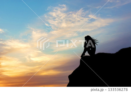 Silhouette of a woman alone on a hill at sunset Silhouette of a woman alone on a hill at sunset 133536278