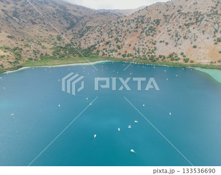 Kournas Lake at foot of mountains crowded with tourists on pedal boats in peak season. Kournas Lake at foot of mountains crowded with tourists on pedal boats in peak season. 133536690