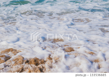 White sea foam created by waves crashing on the shore. Natural marine background White sea foam created by waves crashing on the shore. Natural marine background 133536885