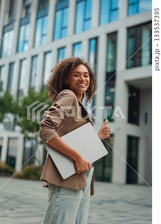 black woman with laptop smiling, female professional confidently approaching office entrance smiling black woman with laptop smiling, female professional confidently approaching office entrance smiling 133537395