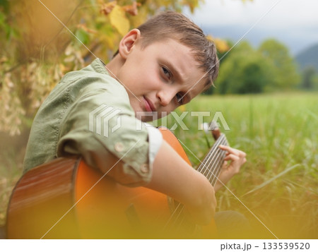 Young Boy Playing Guitar Outdoors in Nature Young Boy Playing Guitar Outdoors in Nature 133539520