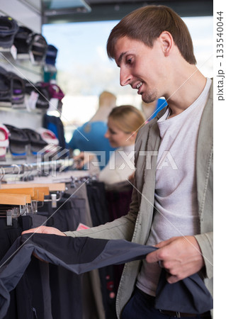 Customer examining pair of hiking trousers in sportswear store Customer examining pair of hiking trousers in sportswear store 133540044