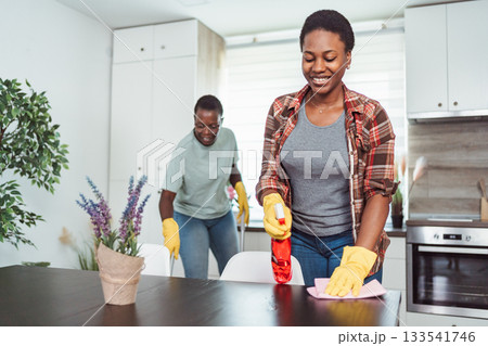 Two African American Women Cleaning the Kitchen Table and Chairs 133541746