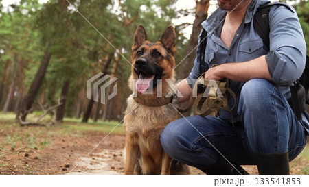 Trekking through the woods, Man and dog relaxing, German Shepherd with owner in forest, Nature escape for two, Best friends outdoors, Bonding in fresh air, Dog owner adventure, Leisure time in the 133541853