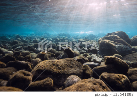 Underwater scene with stones and sun rays in blue sea. 133541898