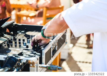 A DJ musician near the music console at a disco on the beach A DJ musician near the music console at a disco on the beach 133542322