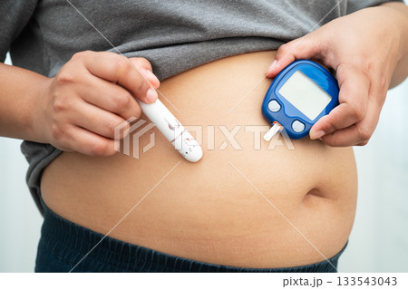 Asian woman injecting herself diabetes injecting insulin in stomach at home. 133543043