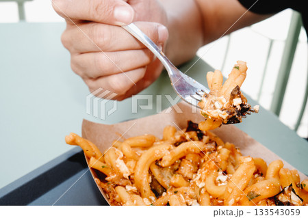 man eating casarecce alla norma outdoors 133543059